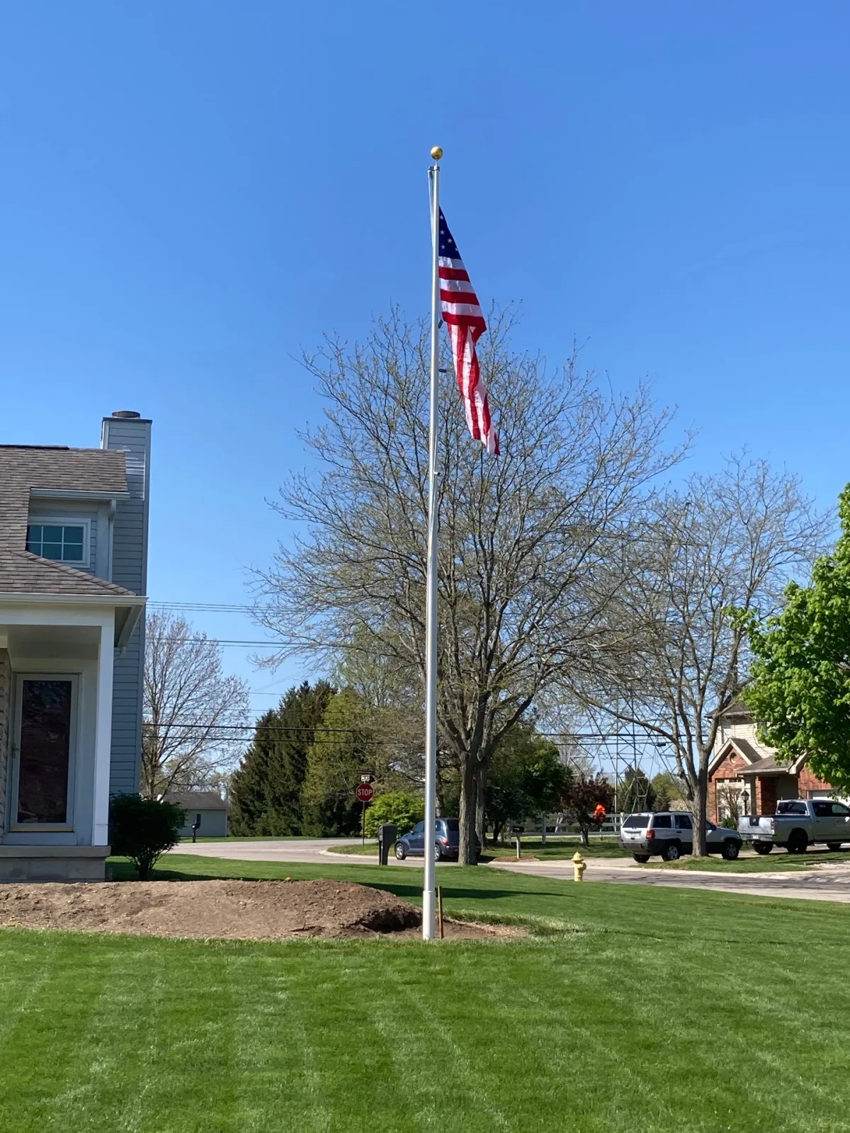 Residential aluminum flagpole installed in suburban neighborhood front yard