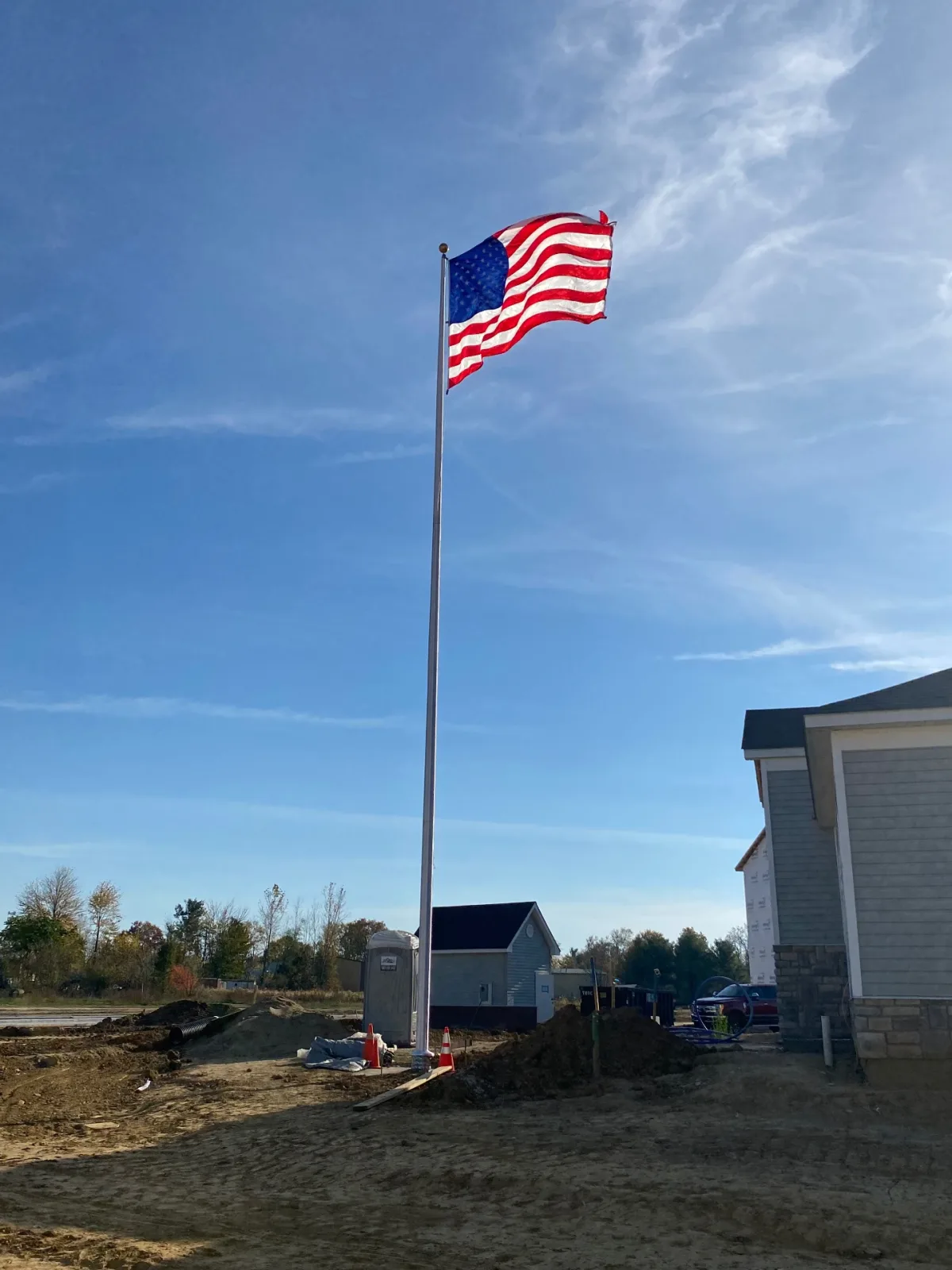 Residential flagpole installed on new construction home site with American flag flying