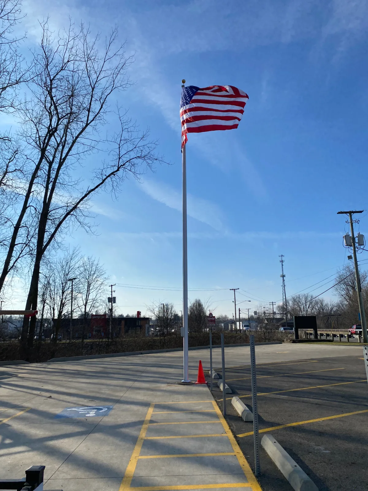 Commercial flagpole installed in business parking lot near roadway