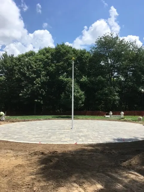 Flagpole installed on circular paver patio