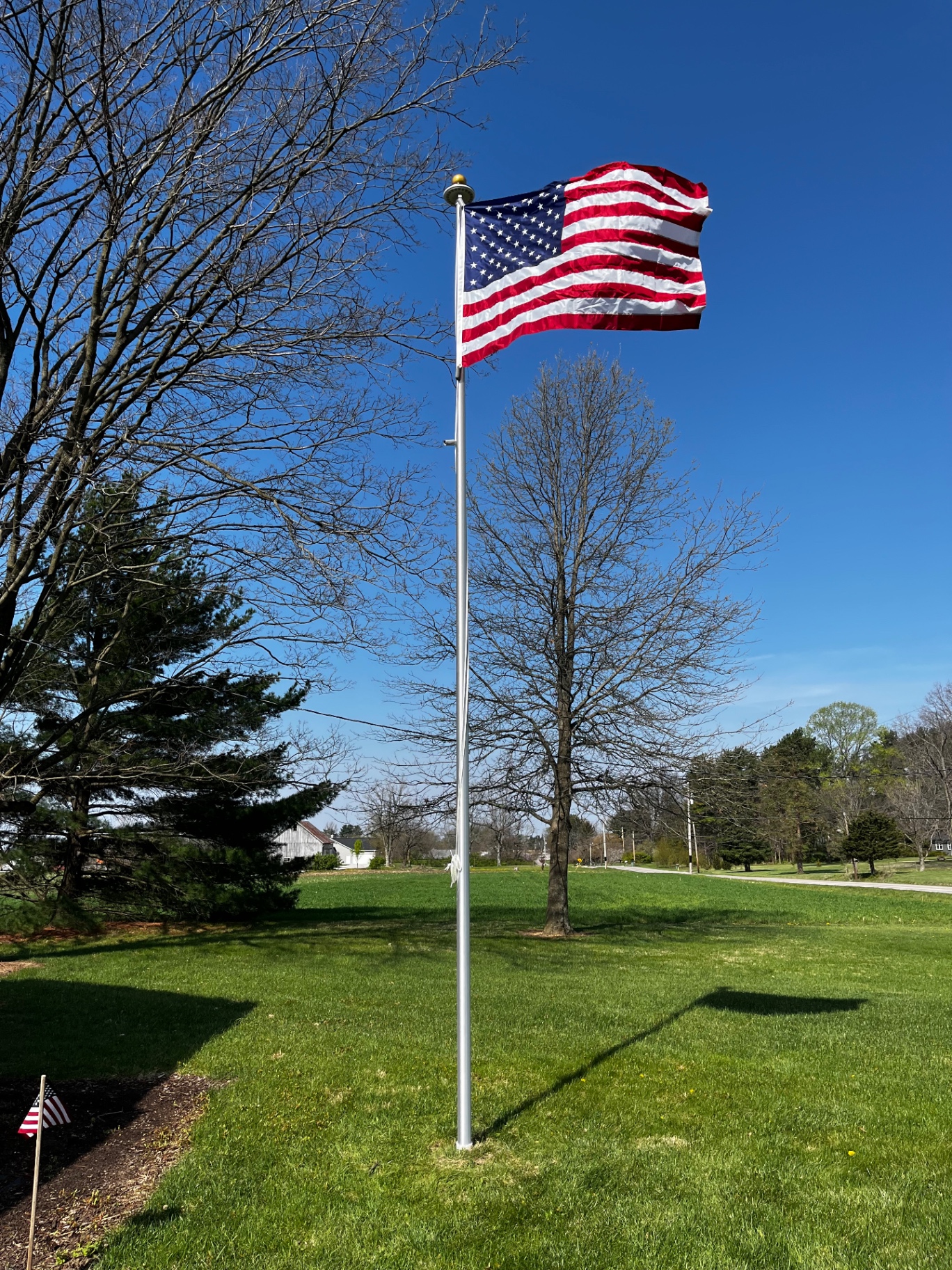 American flag flying on residential aluminum flagpole in open yard