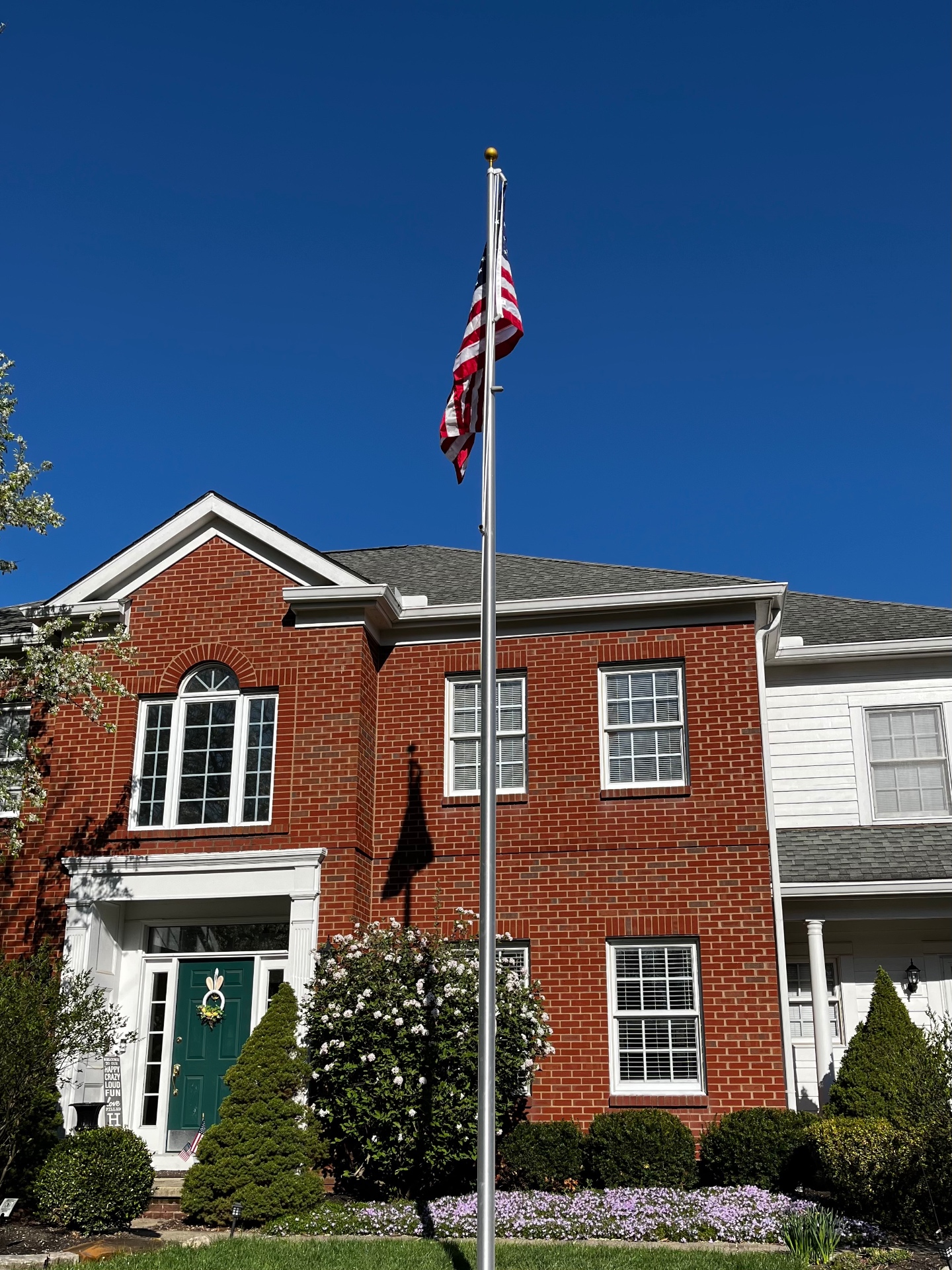American flag on flagpole installed in front of brick home